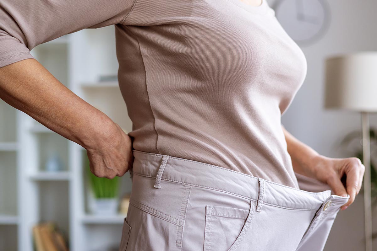 Woman holding loose pants after successful weight loss in Bartlett, IL